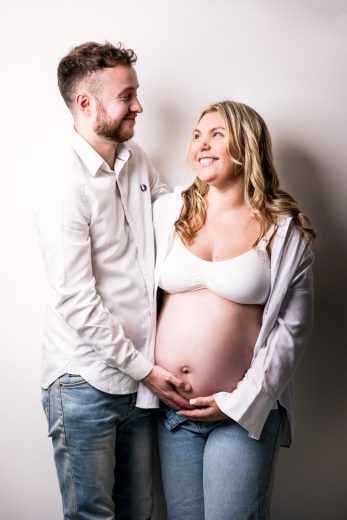 STUDIO COUPLE PHOTOS FOR MATERNITY SESSION ON WHITE BACKGROUND